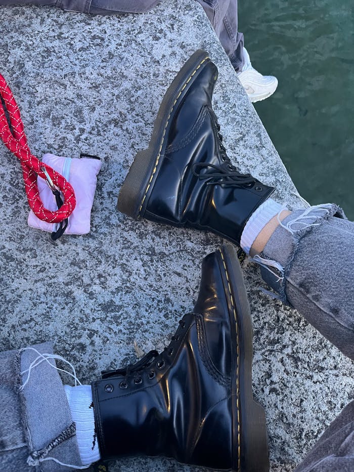 Stylish black leather boots paired with rolled-up jeans on a stone surface.