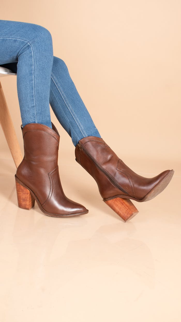 Elegant brown leather boots with wooden heels paired with blue jeans.