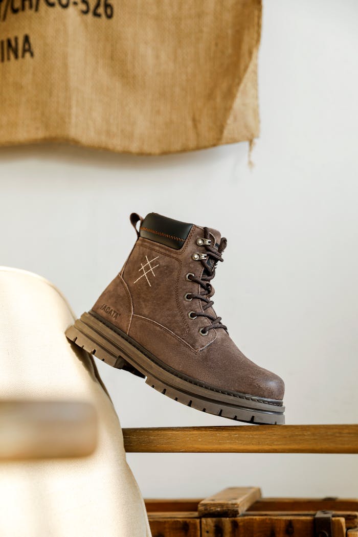 Brown leather hiking boot showcased on wooden surface for fashion concept.